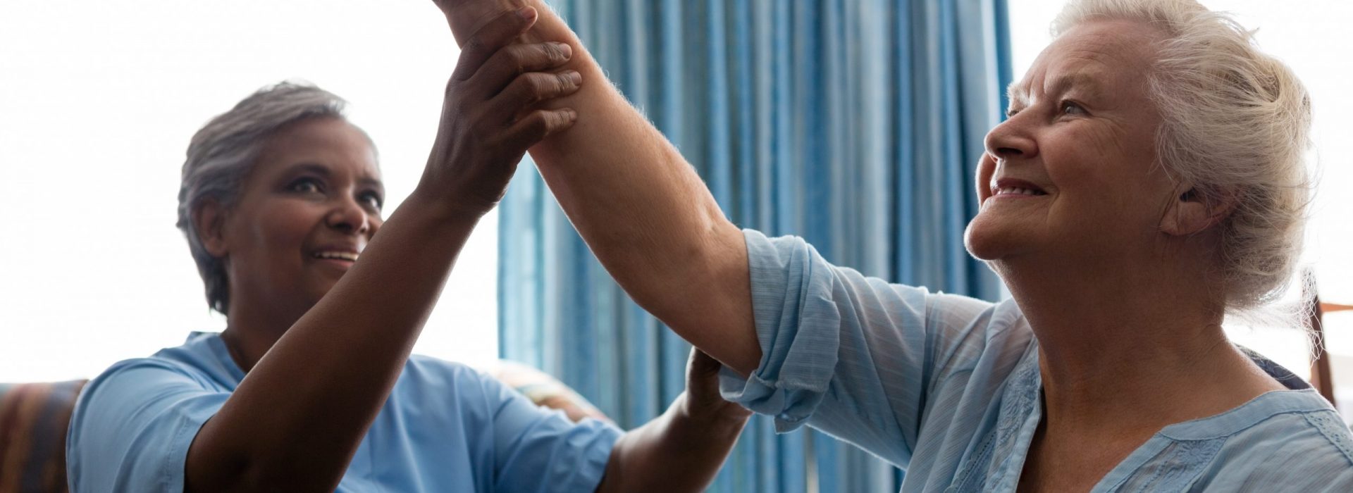 Nurse helping senior woman in flexing muscles at nursing home